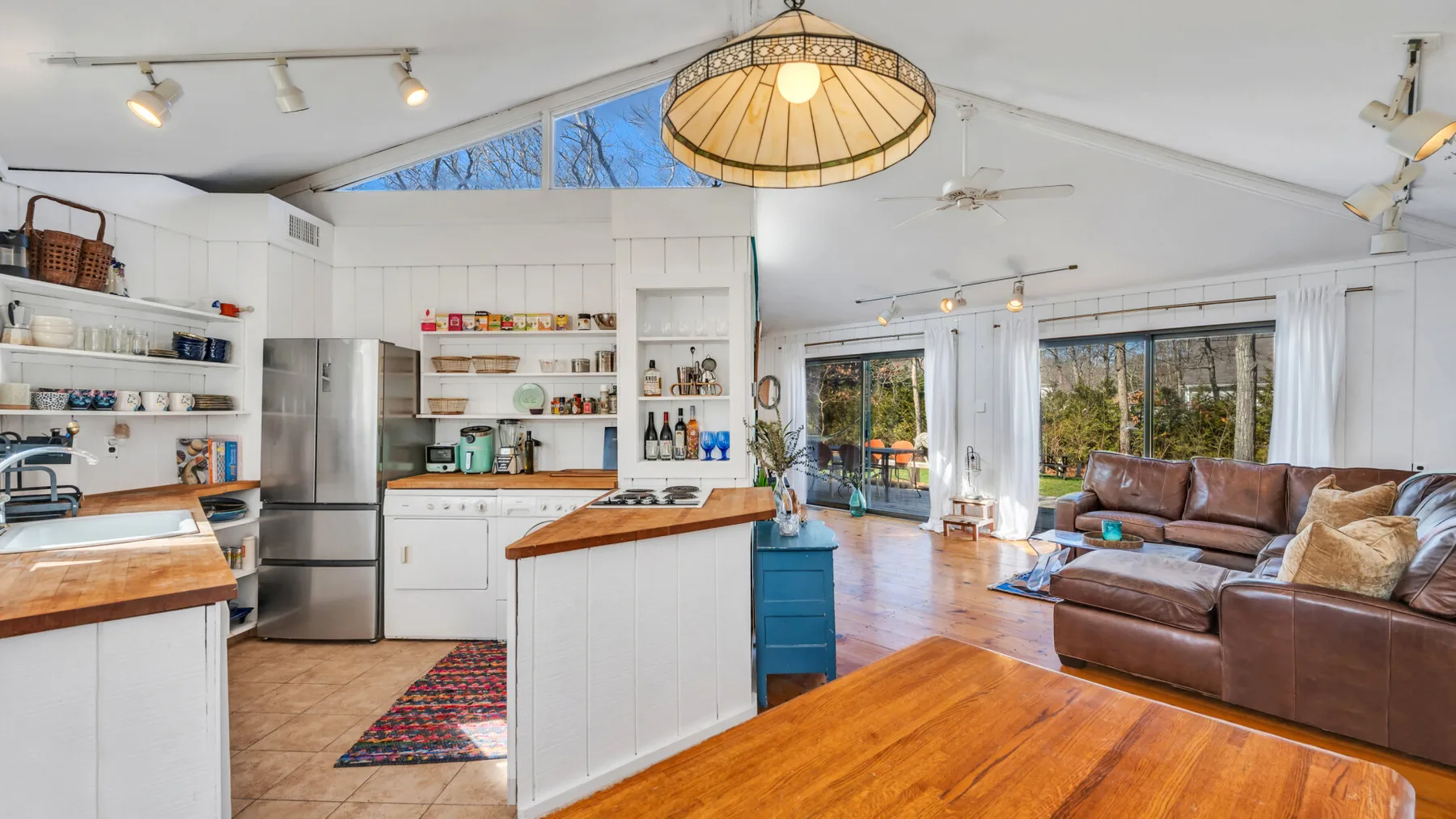 Una luminosa cocina abierta al salón, con una isla central y asientos.