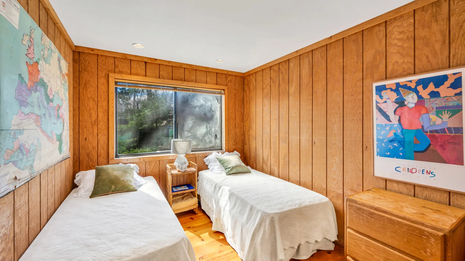 Un dormitorio con paneles de madera, dos camas y una ventana.