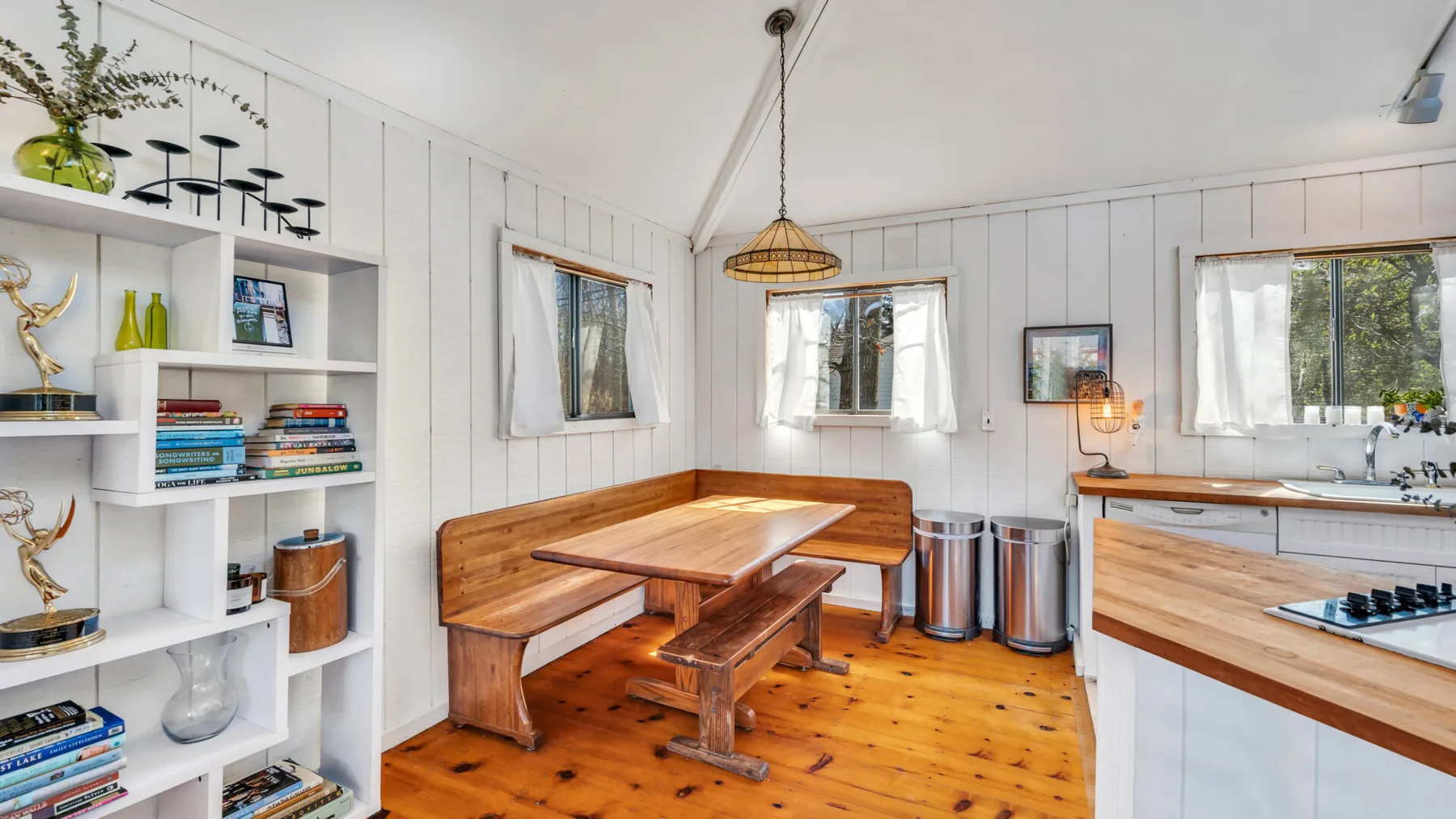Un comedor luminoso con una mesa de madera, estanterías empotradas y ventanales.