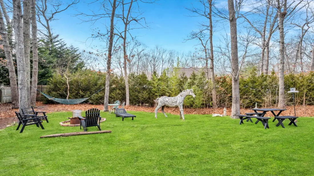 A grassy outdoor seating area with picnic tables and a decorative horse statue.