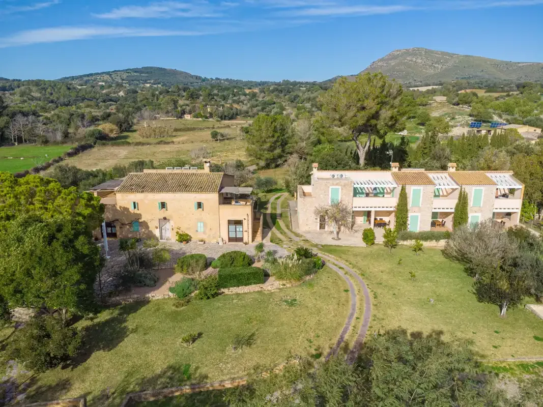 Aerial view of several buildings amid green grounds and rolling hills.
