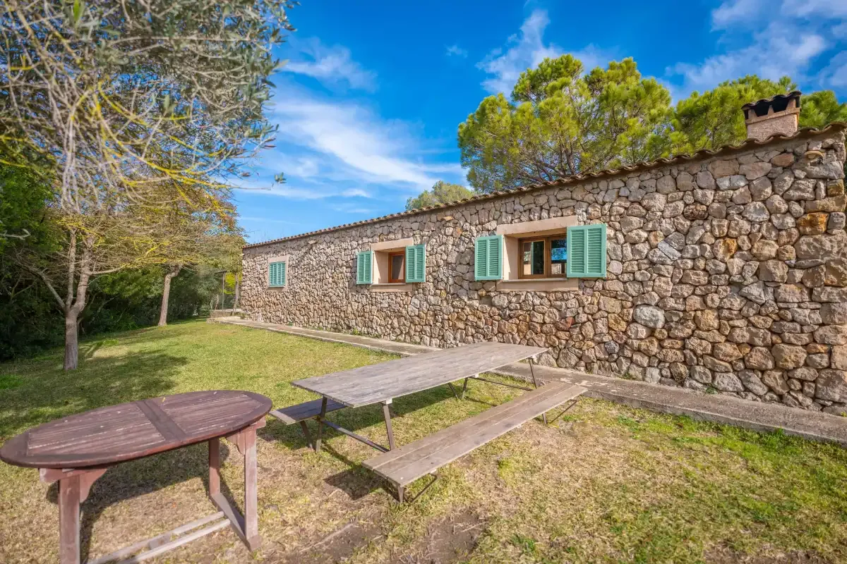 A stone building beside an outdoor picnic table and grassy yard.