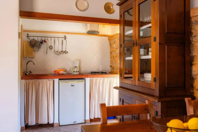 A warm kitchen with a counter, hanging utensils, and a wooden cabinet.