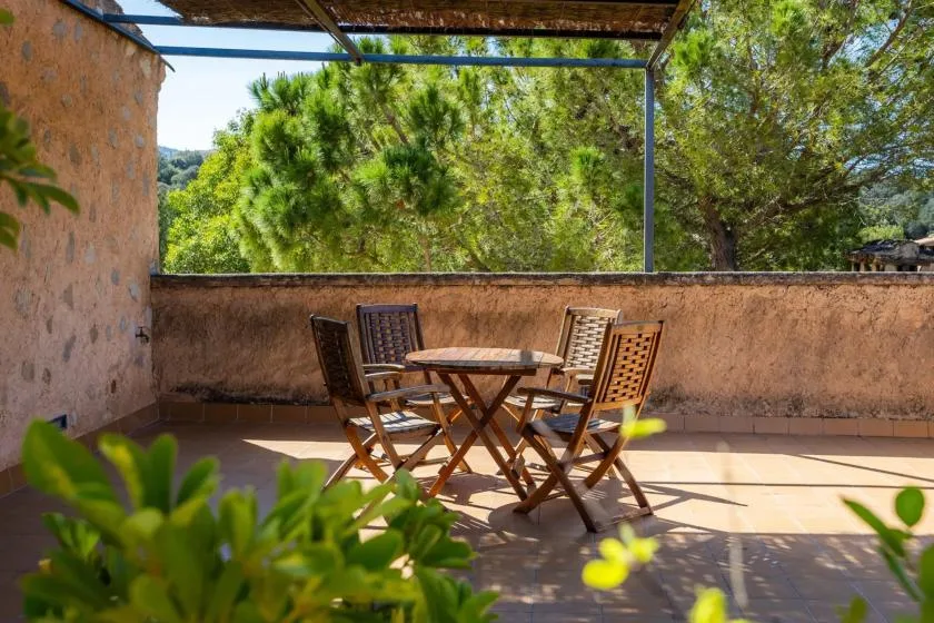 A sunny outdoor patio with a wooden table and seating beneath a canopy.