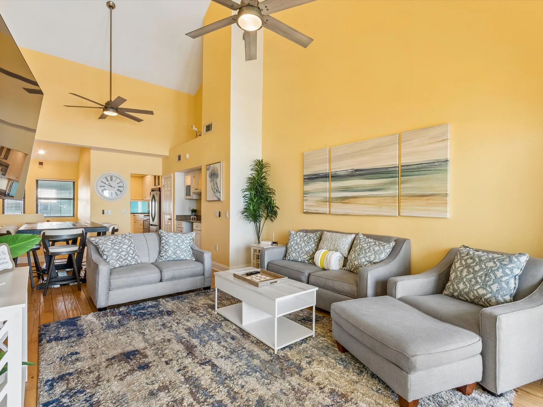 A bright living room with seating, a coffee table, and an open dining area.