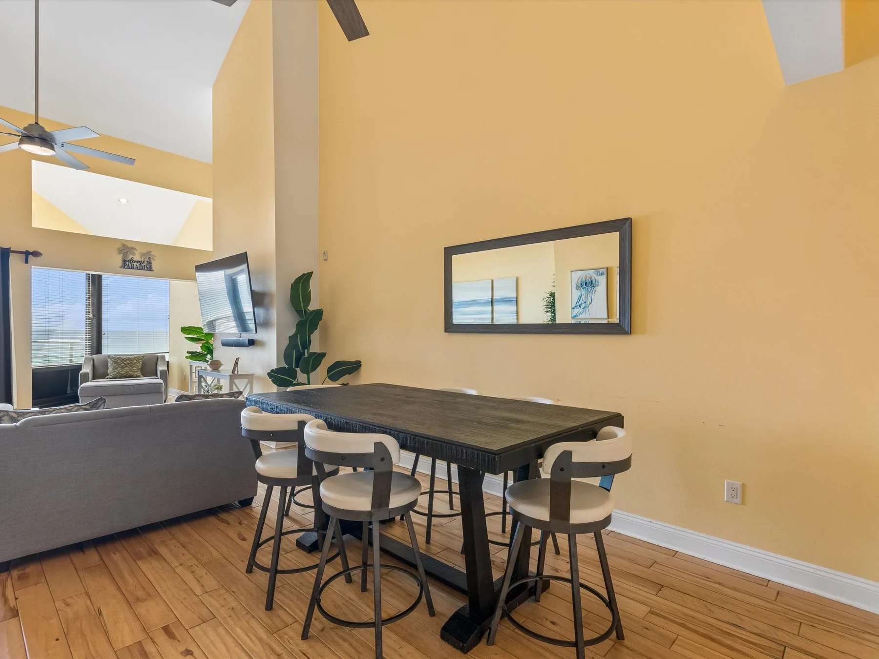 Una mesa de comedor con asientos está junto a una zona de estar en una sala luminosa y abierta.