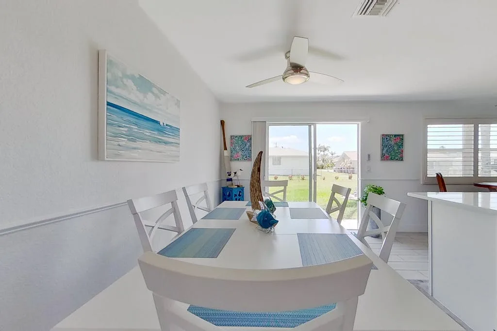 A bright dining area with a white table and sliding glass doors.