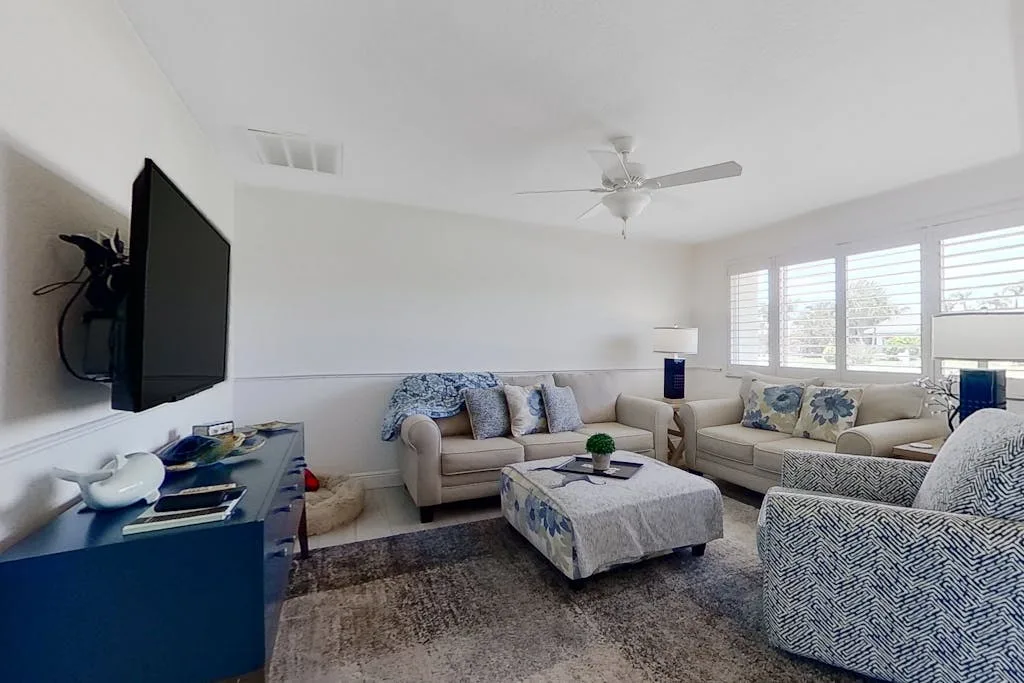 A bright living room with seating arranged around a coffee table and large windows.