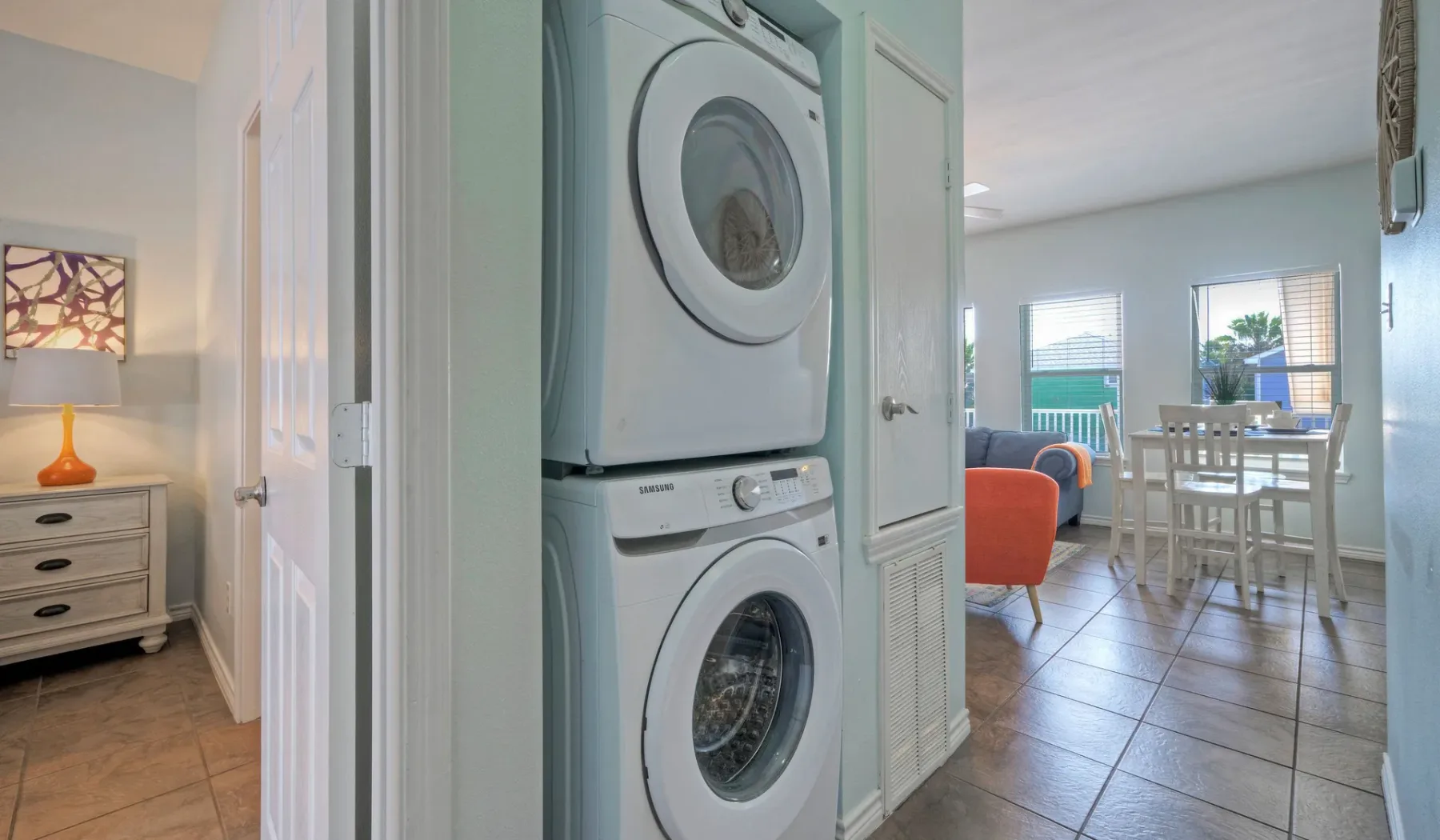 A laundry nook with a stacked washer and dryer opens onto a dining area.