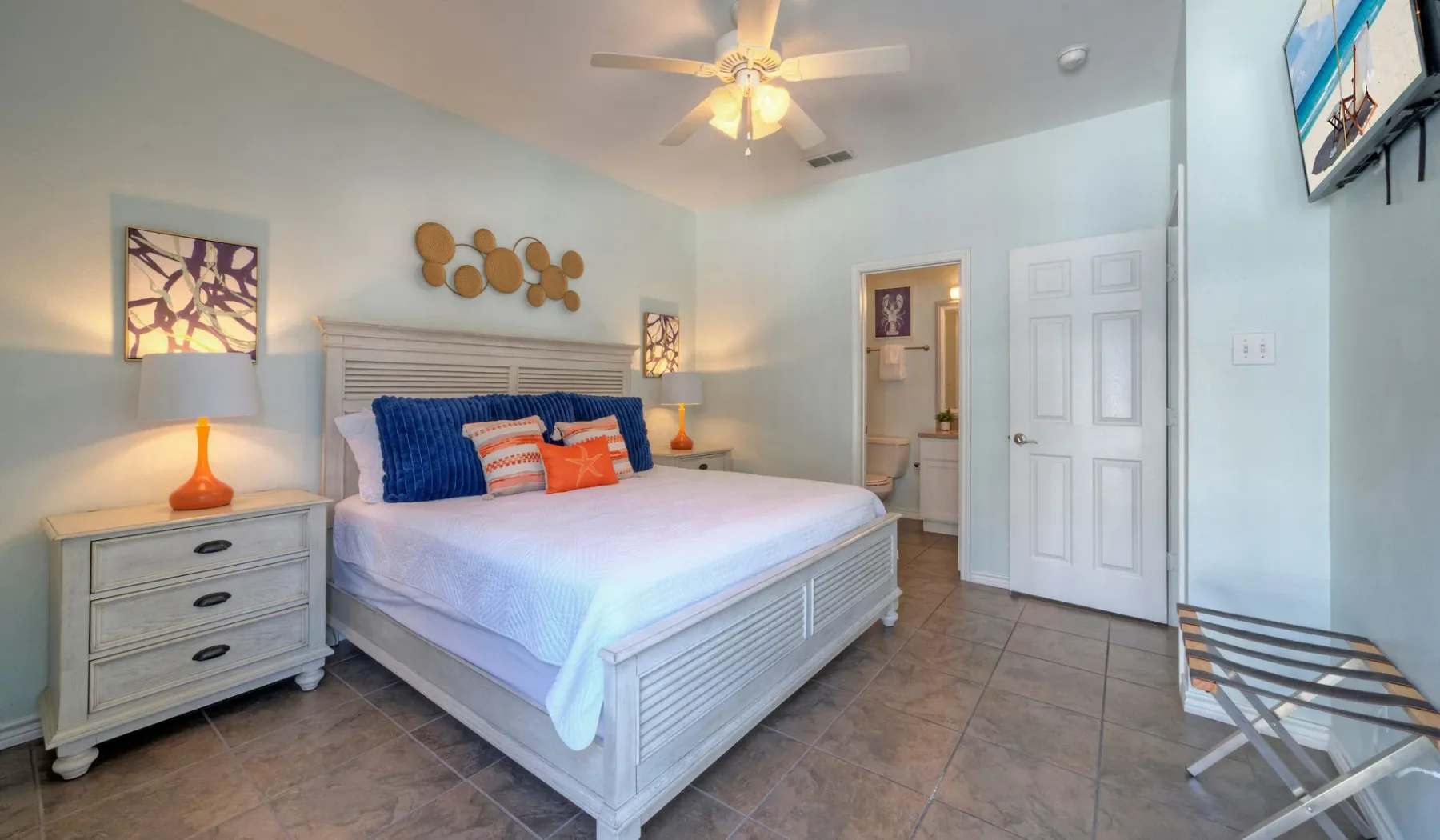 A bedroom with a large bed, bedside tables, and a ceiling fan.