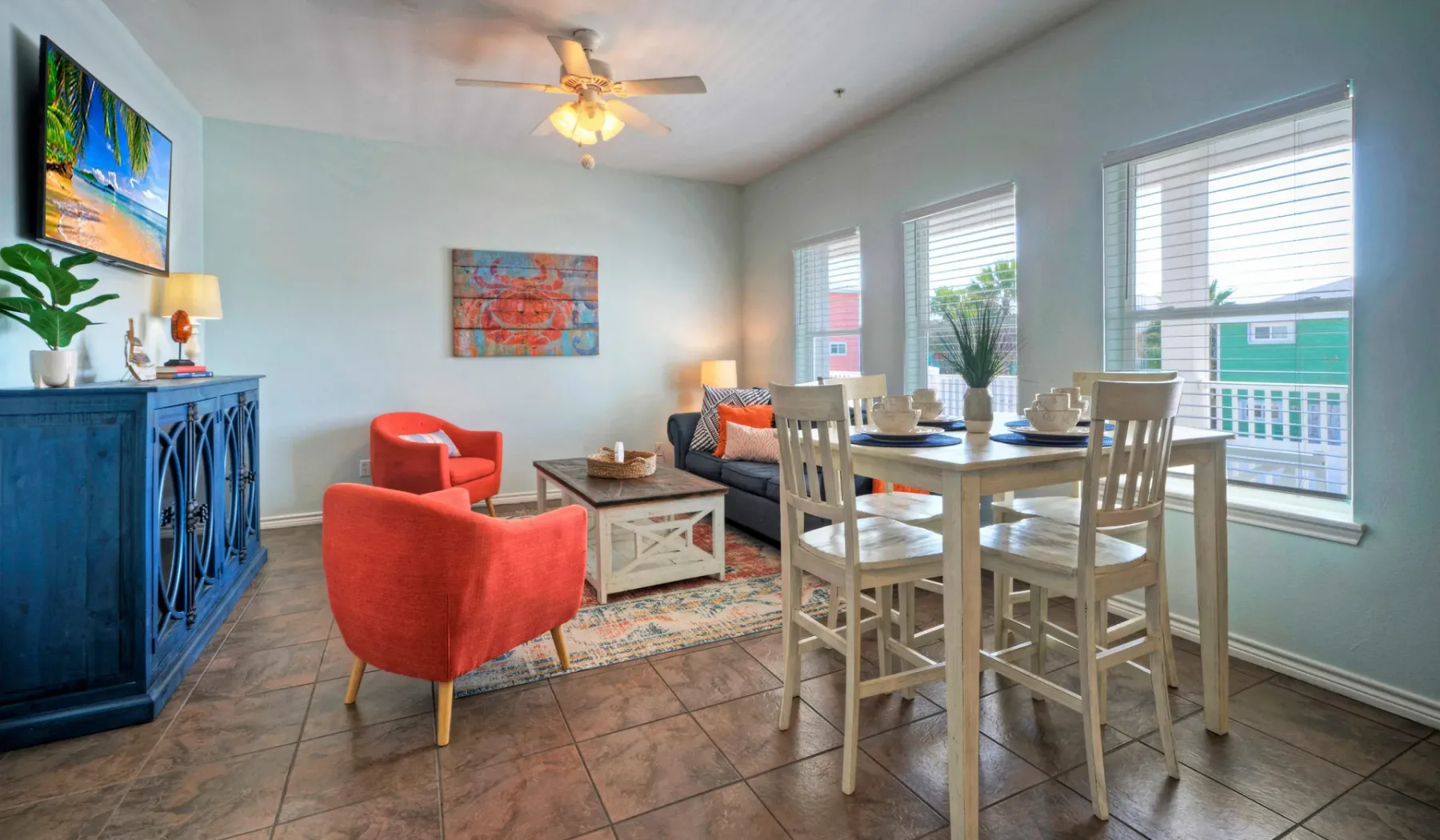 A bright living and dining area with a table, seating, and large windows.