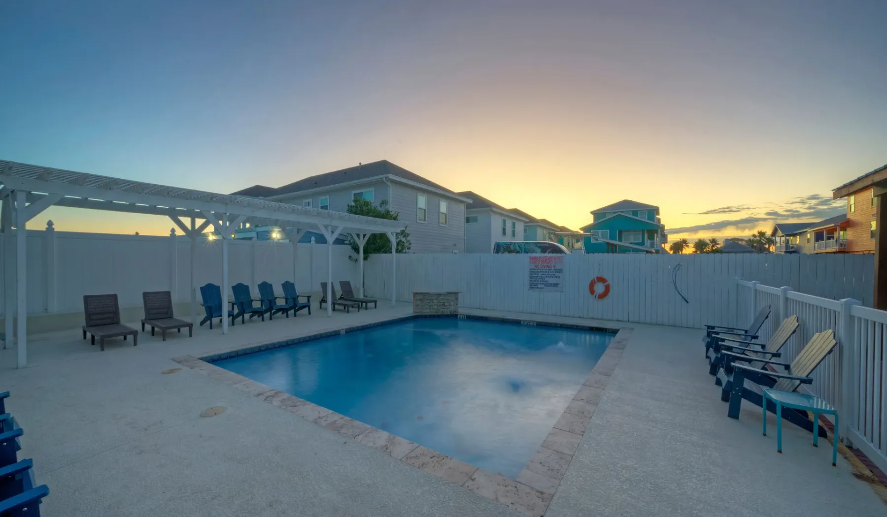 An outdoor swimming pool sits beside rows of seating at sunset.
