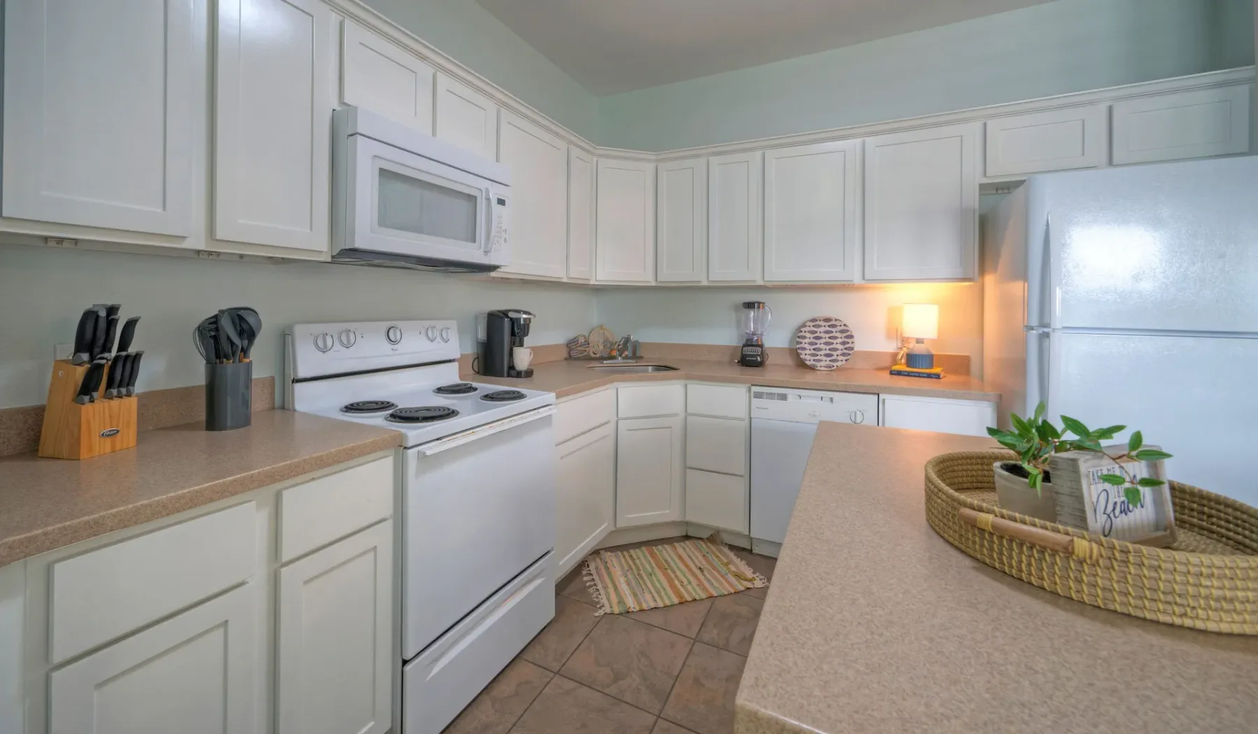 A bright kitchen with white cabinets, a stove, and a countertop plant.