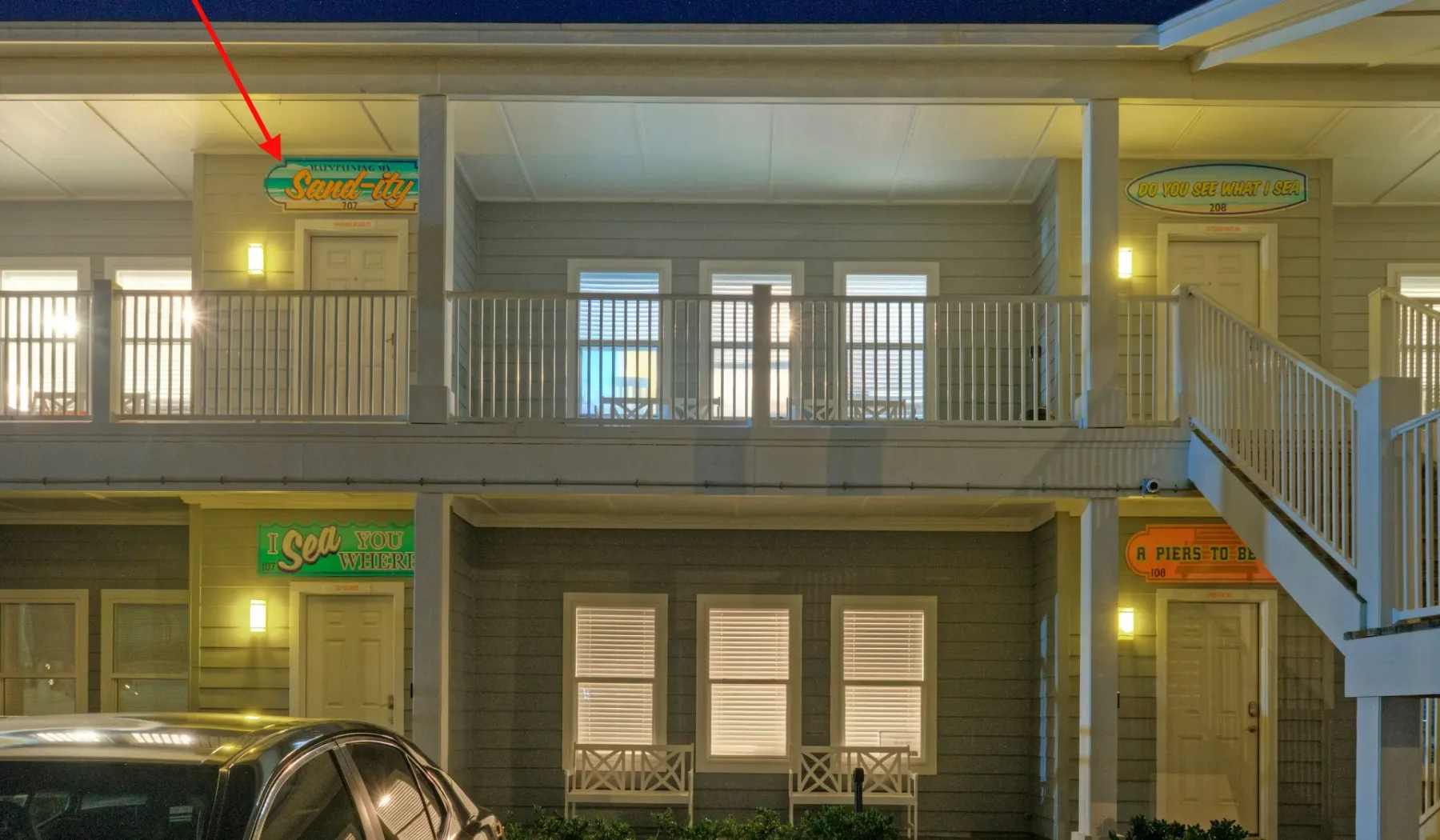 A two-story building facade with exterior walkways and illuminated signs.
