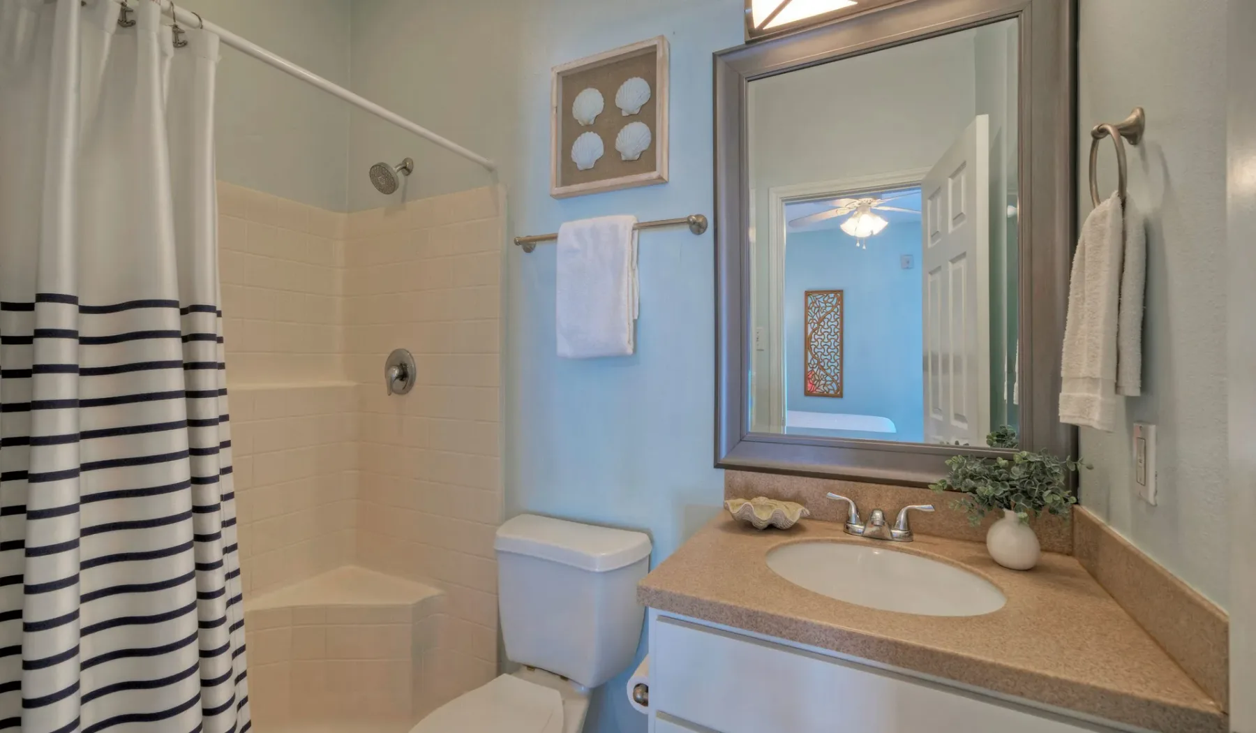A bathroom with a striped shower curtain, vanity, and large mirror.