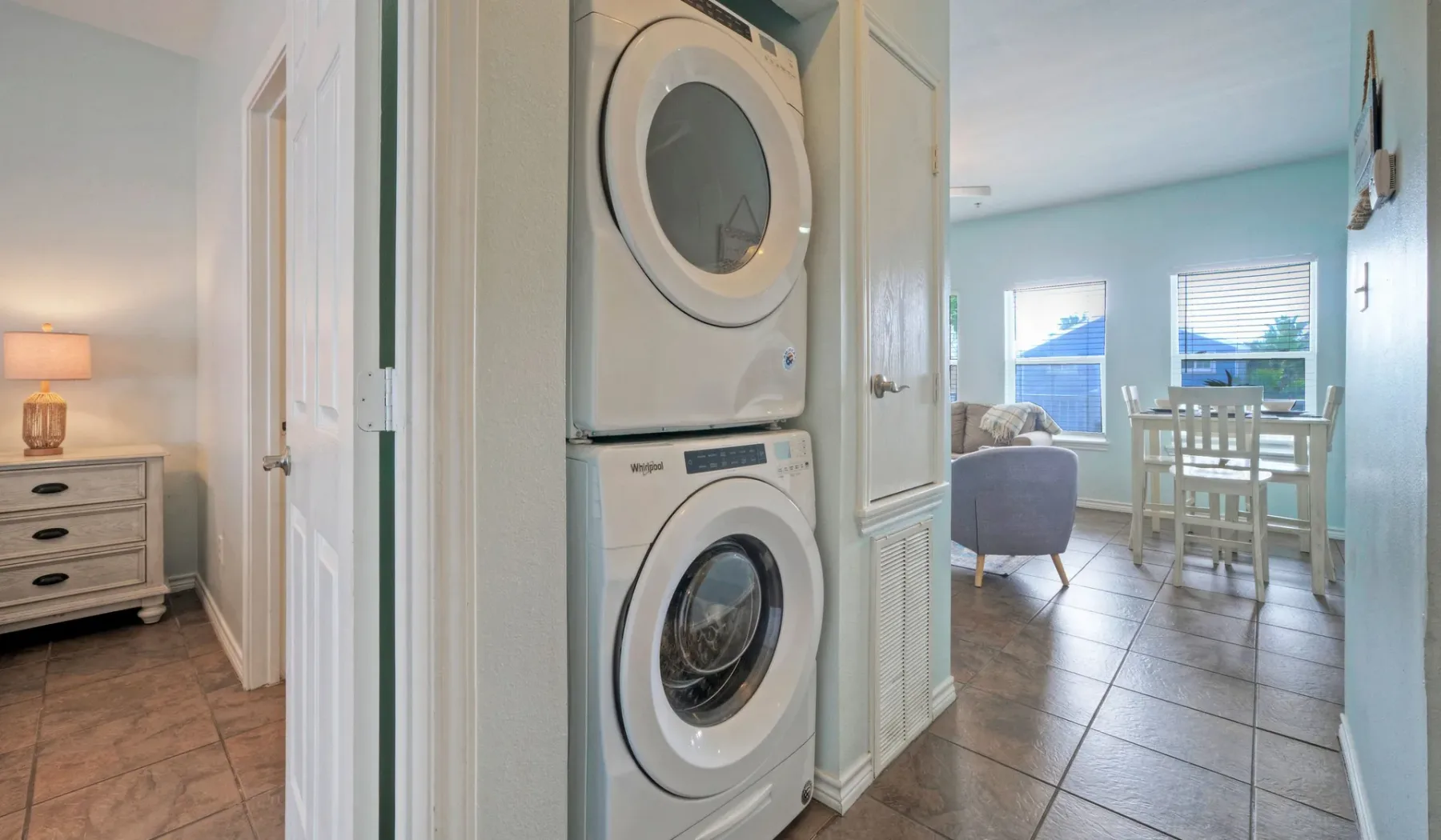 A laundry area opens onto a dining space with a table and chairs.