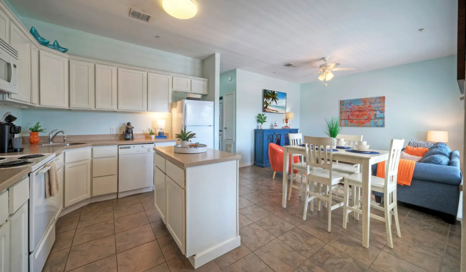 An open-plan kitchen and dining area with a blue seating area beyond.