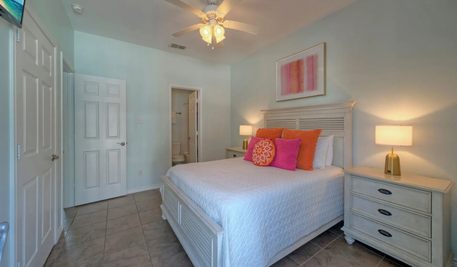 A bedroom with a neatly made bed and colorful accent pillows.