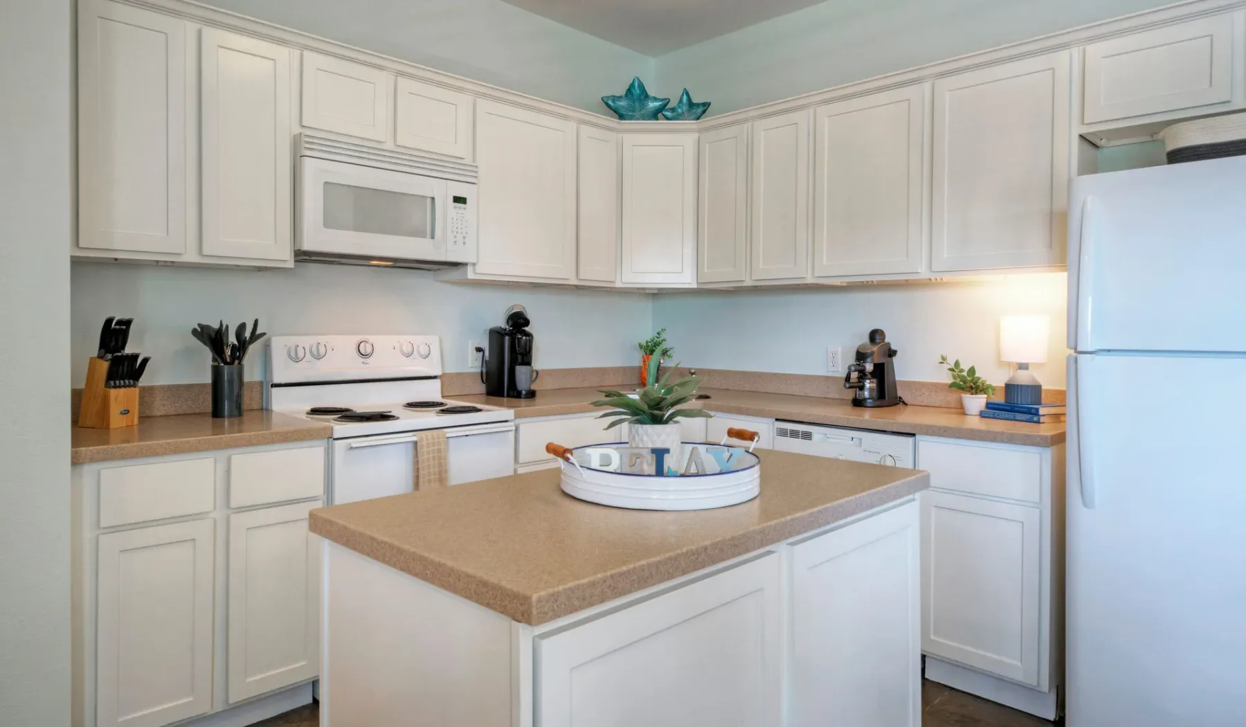 A bright kitchen with white cabinets, appliances, and a central island.