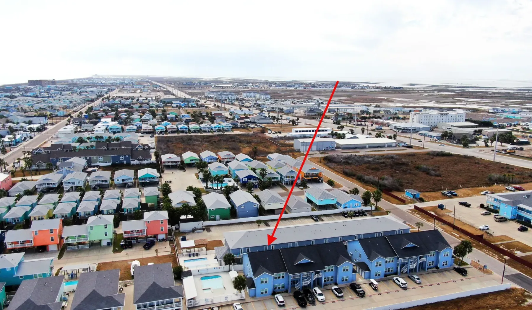 Aerial view of a blue apartment building among homes and streets.