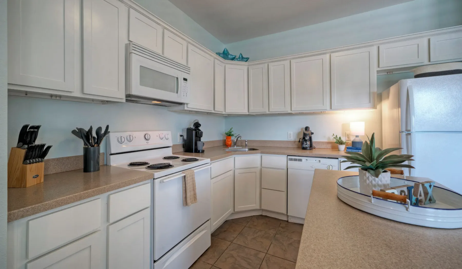 A bright kitchen with white cabinets, a countertop, and a central island.
