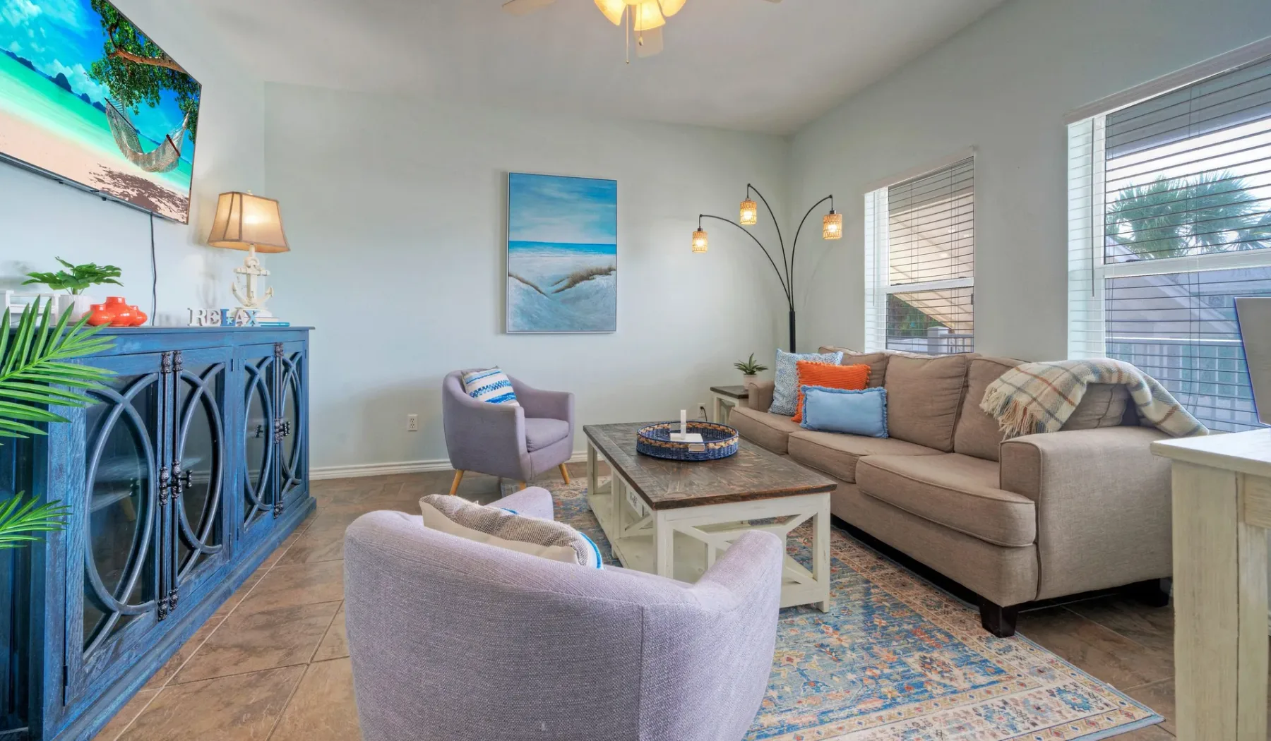 A bright living room with seating around a coffee table and large windows.