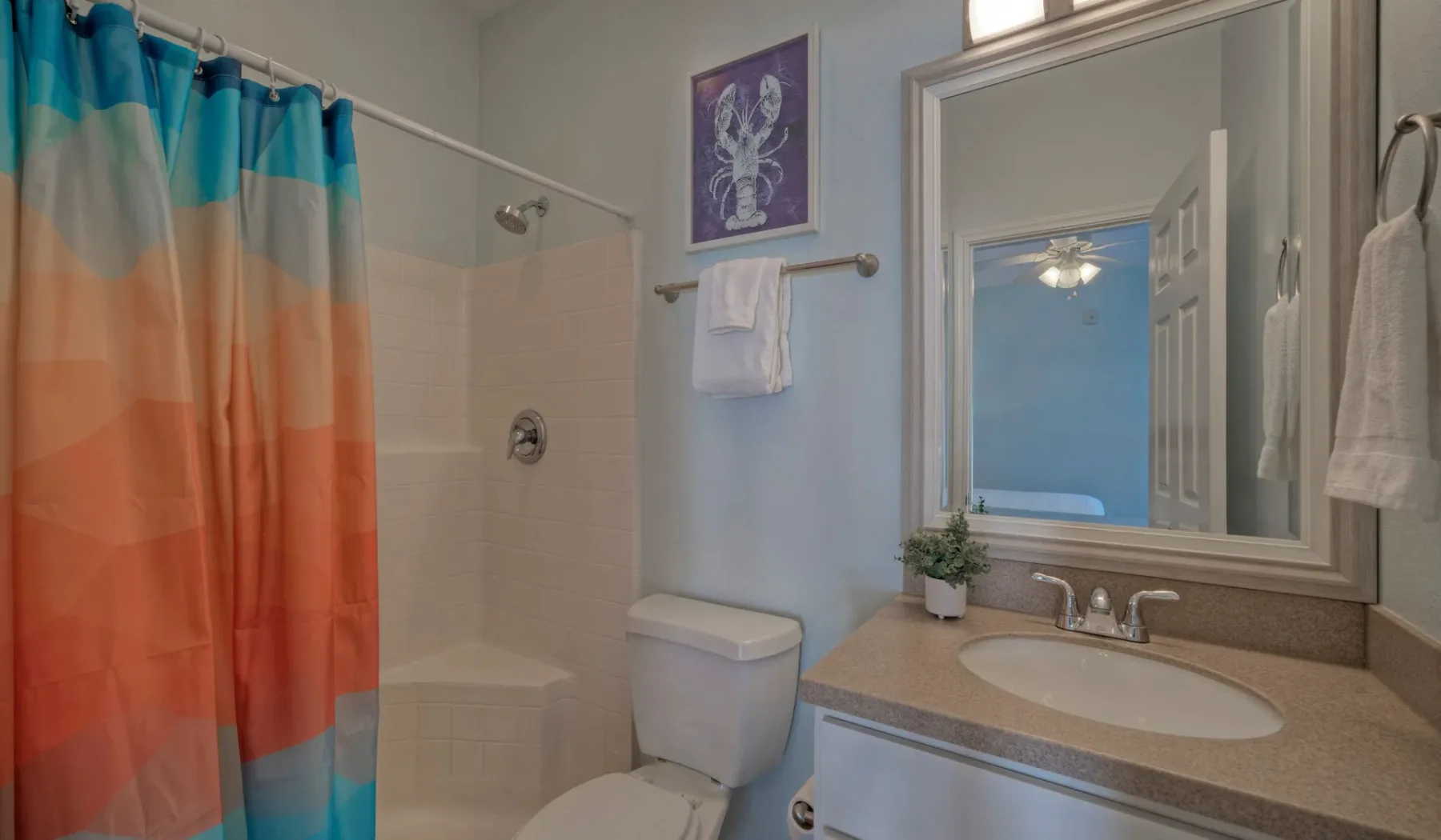 A bathroom with a colorful shower curtain, toilet, and sink.