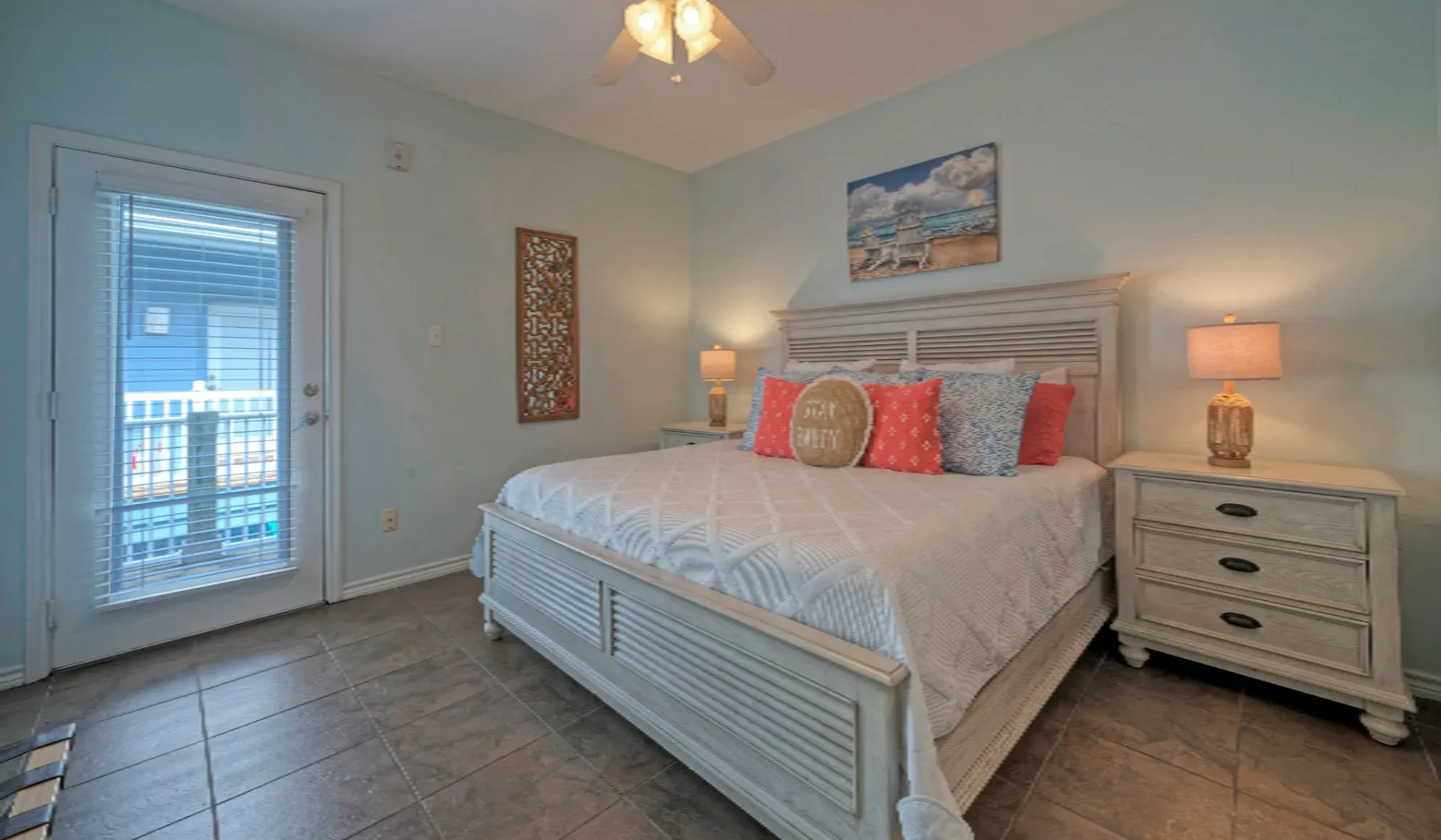 A bedroom with a light-colored bed, colorful pillows, and matching bedside tables.