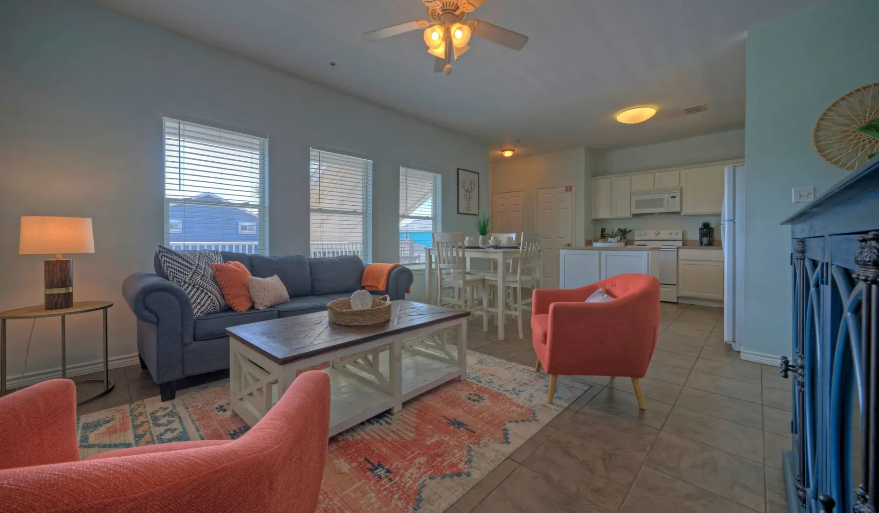 A living room opens into a dining area and kitchen, with seating around a coffee table.