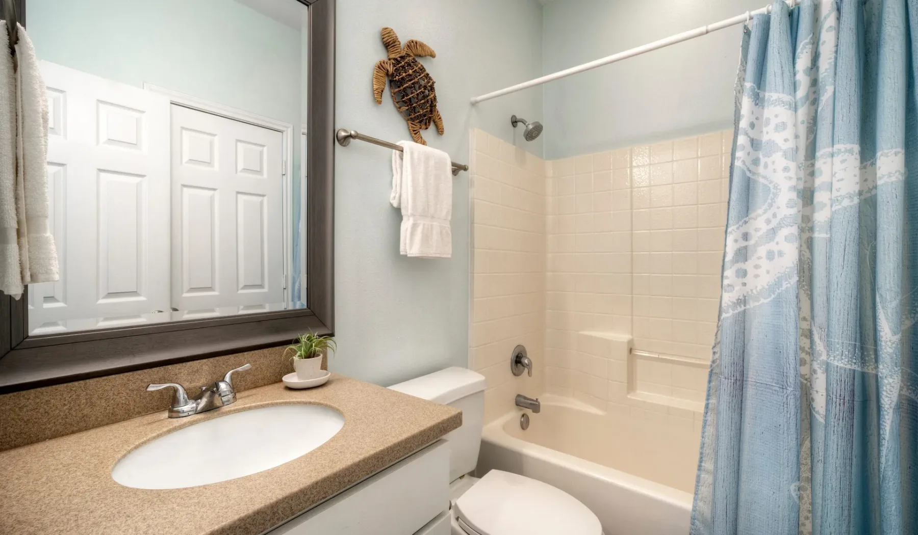 A bathroom with a sink, mirror, and bathtub behind a shower curtain.