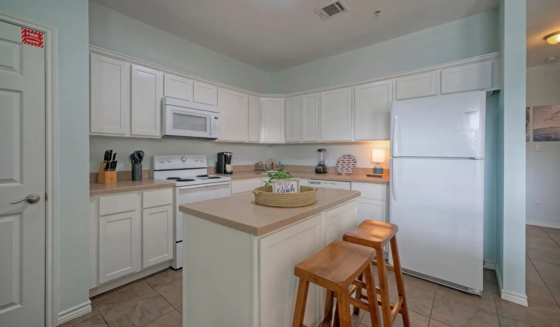 A bright kitchen with white cabinets, appliances, and a central island.
