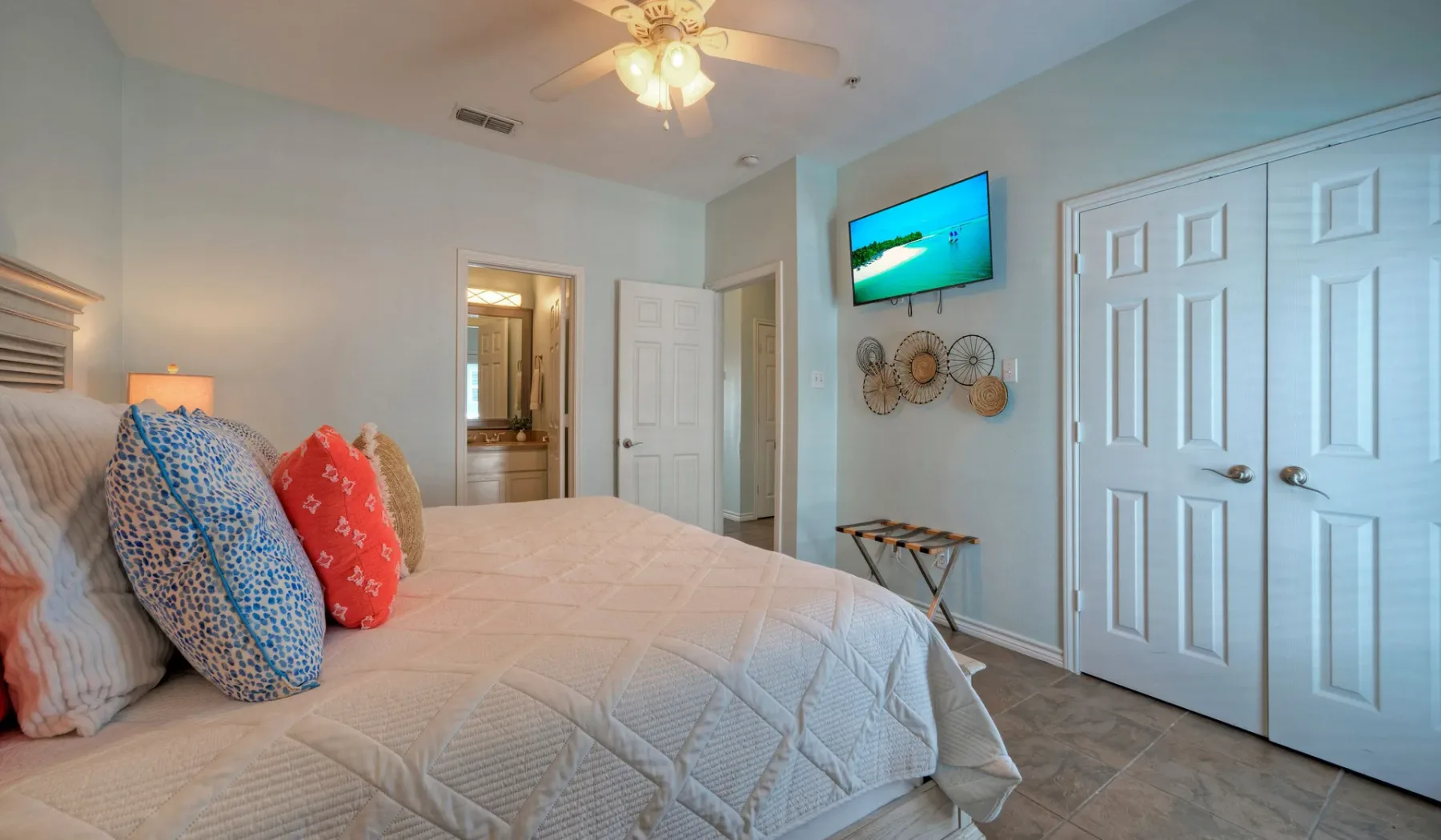 A bedroom with a bed, wall-mounted television, and closet doors.