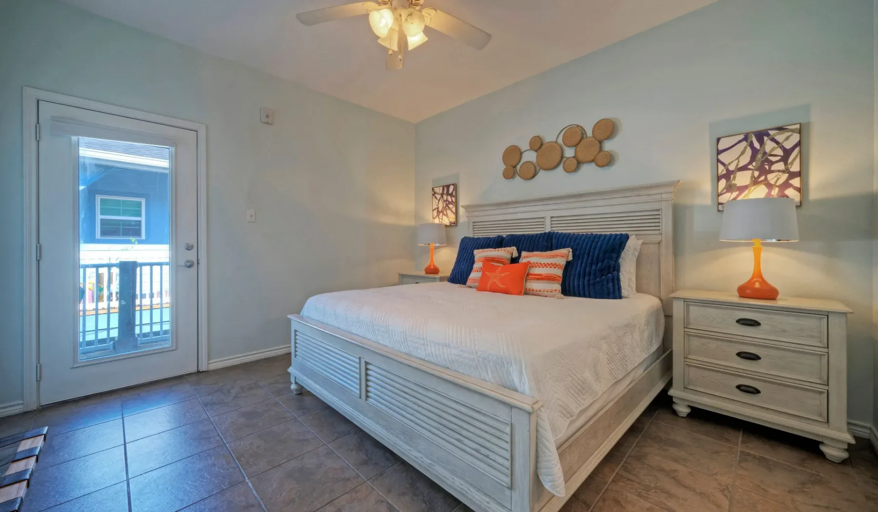A bedroom with a large bed, colorful pillows, and a bedside table.