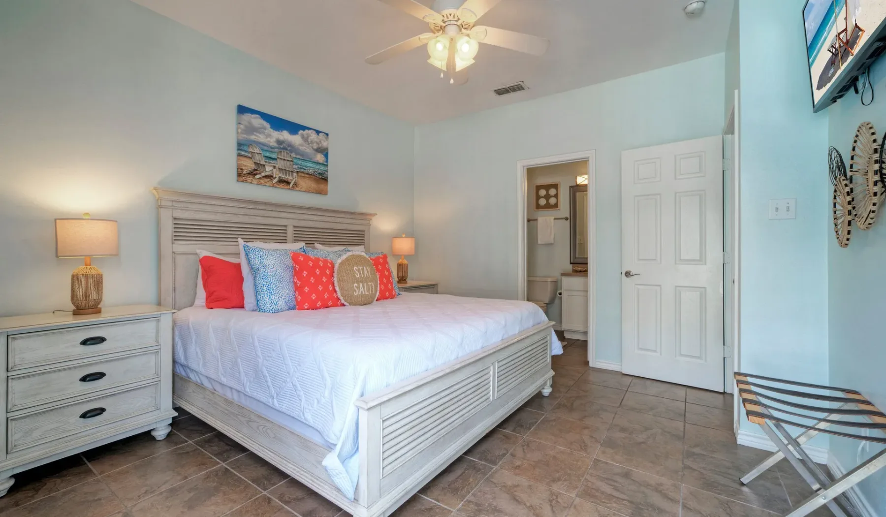 A bedroom with a large bed, colorful pillows, and bedside lamps.