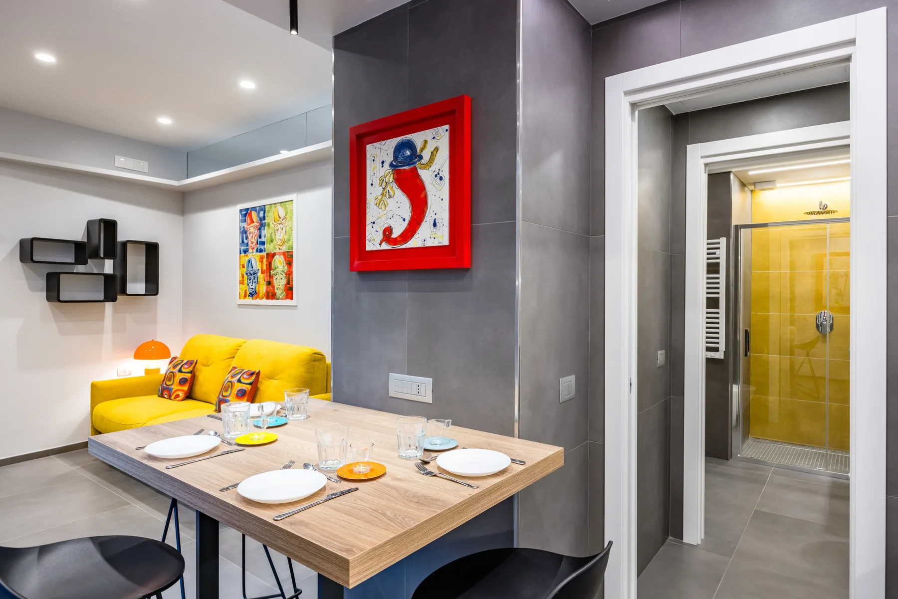 Una luminosa sala de estar y comedor con mesa, asientos amarillos y cuadros.