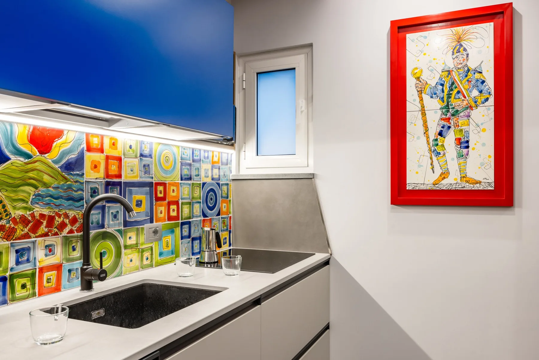 Una cocina colorida con salpicadero de azulejos y una obra enmarcada.