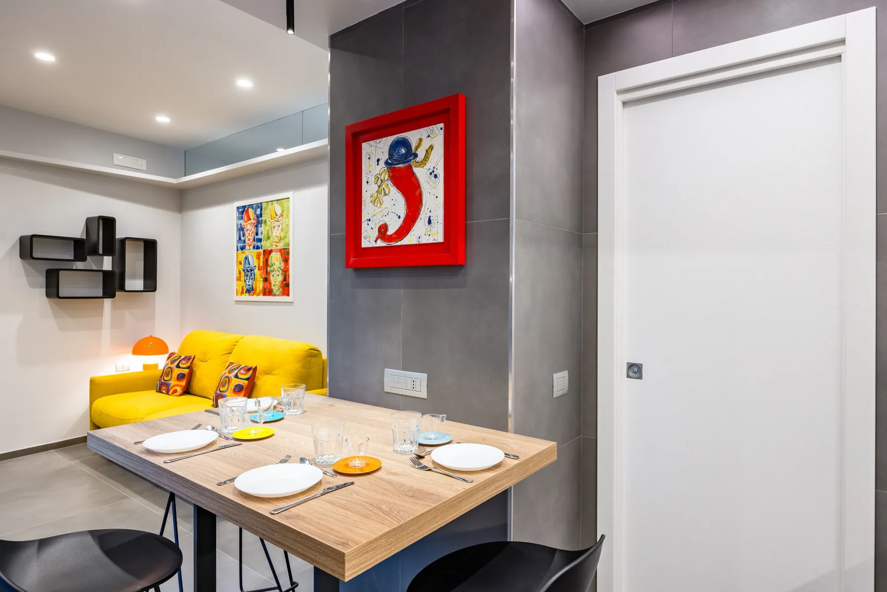 Comedor con una mesa de madera y asientos amarillos junto a una puerta blanca.