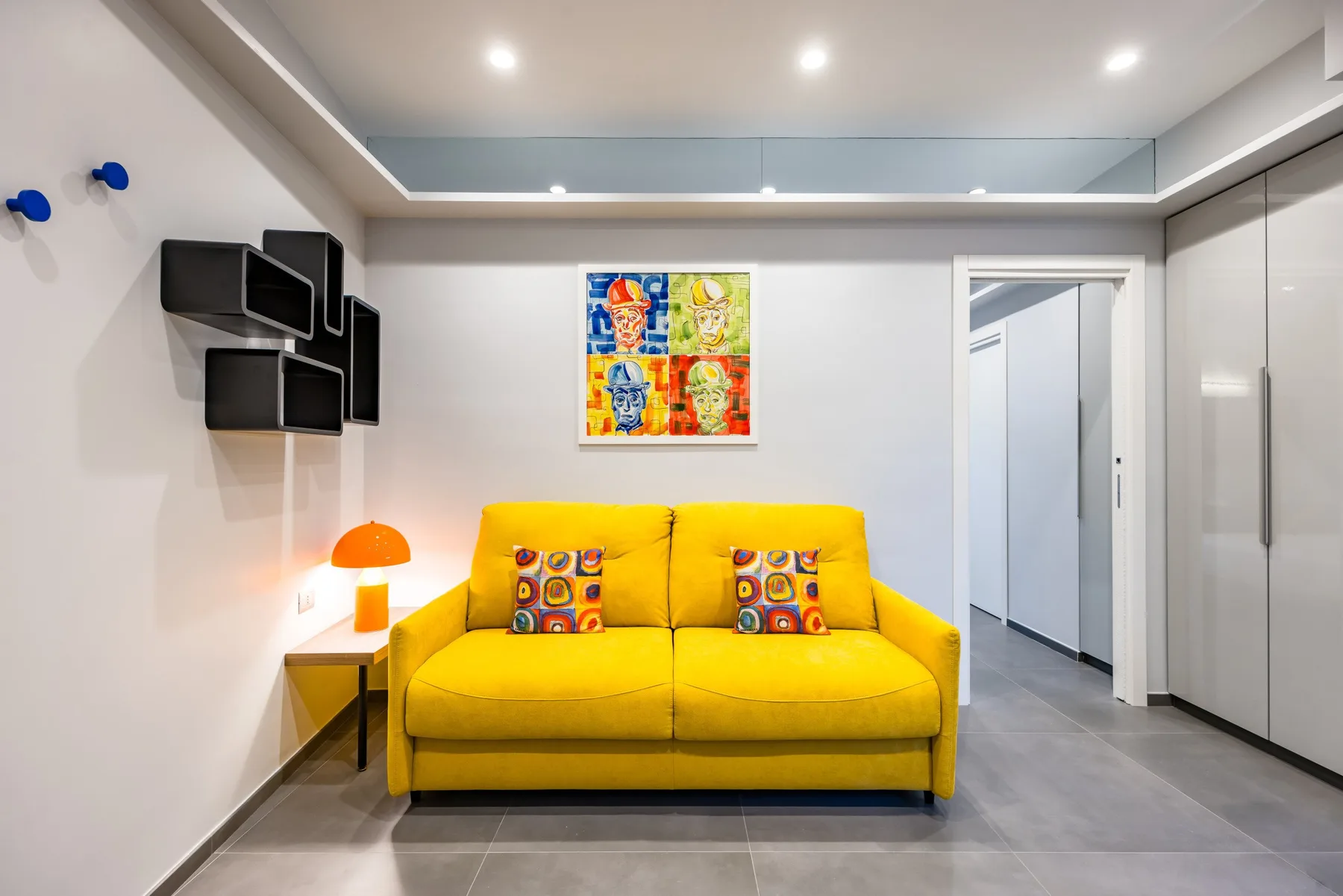 Una sala luminosa con asientos amarillos y arte colorido en la pared.