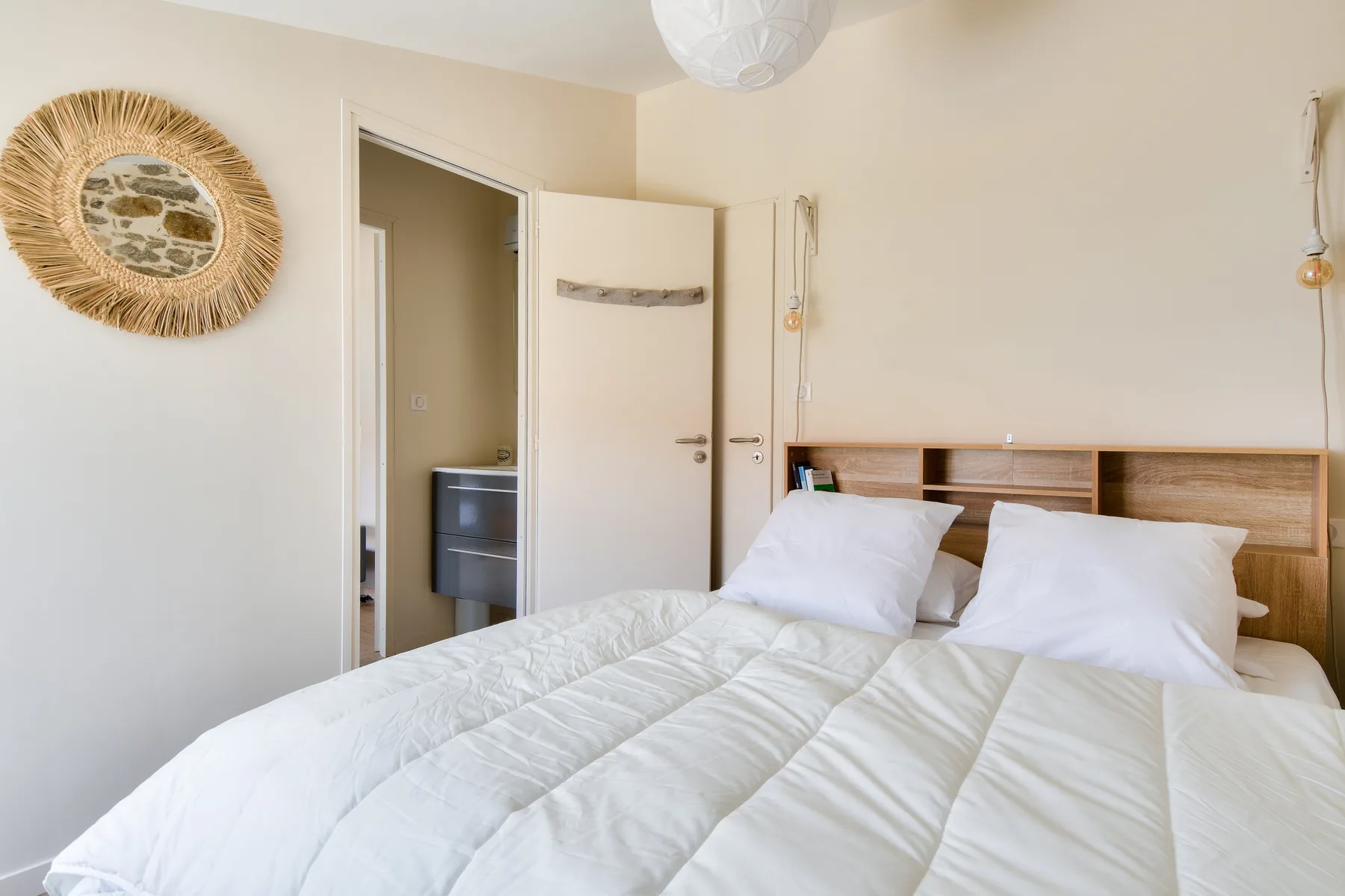 A bedroom with a bed, white bedding, and a wooden headboard.