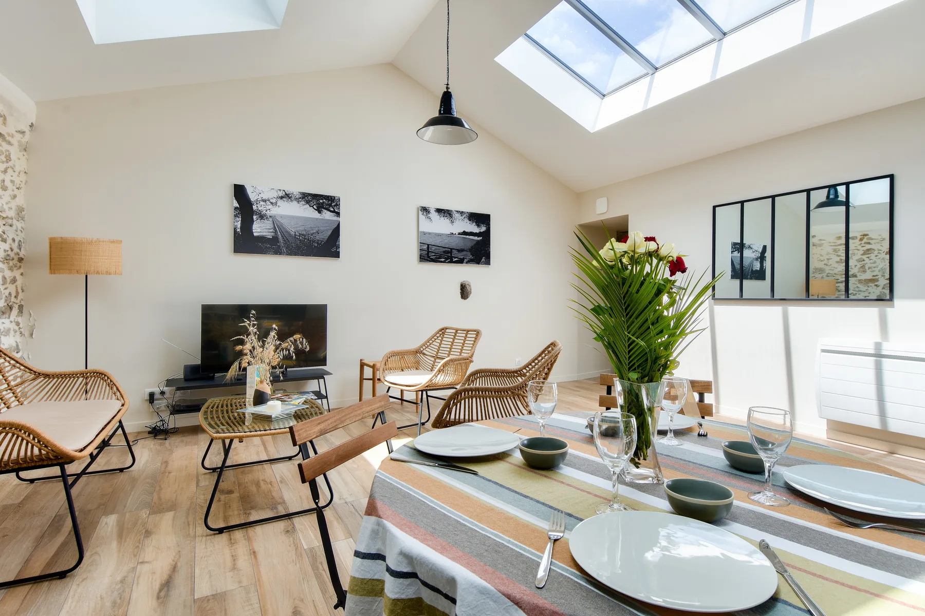 A bright living and dining area with seating, a table, and large skylights.