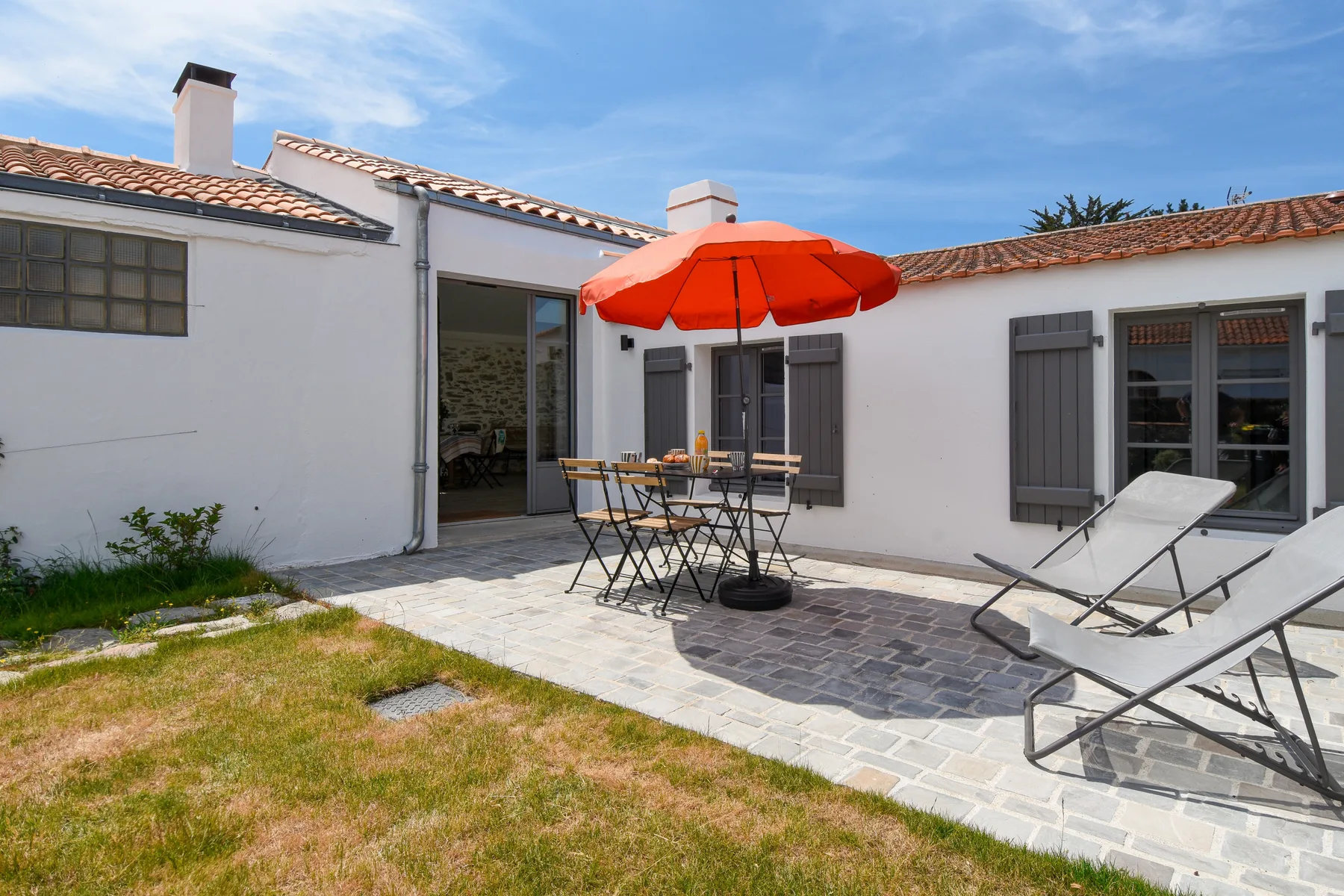 A sunny patio with outdoor seating and a red umbrella.