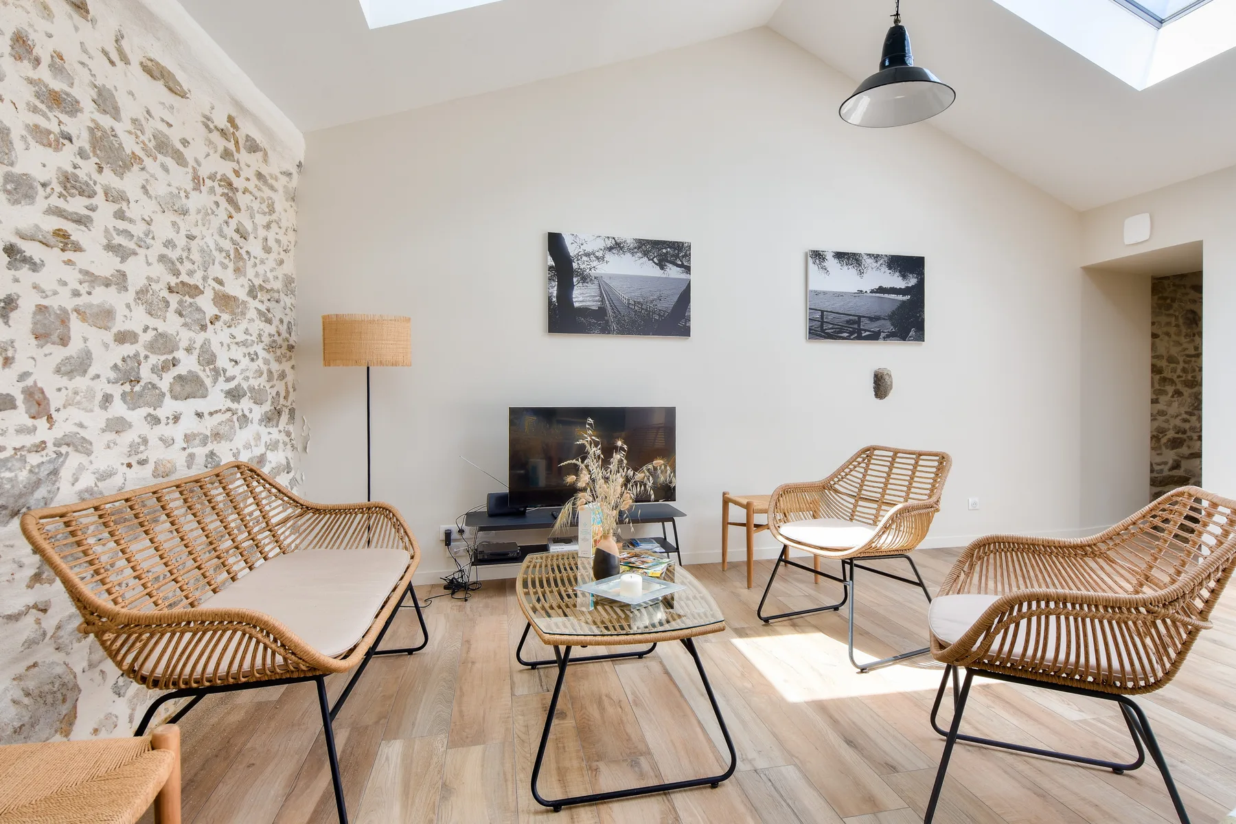 A bright living room with wicker seating and a glass coffee table.