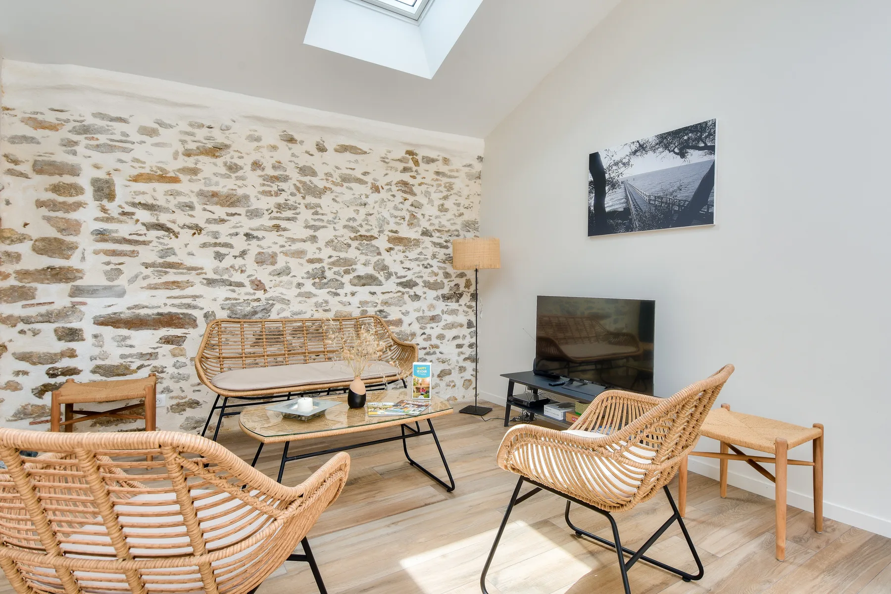 Living room with woven seating, a television, and an exposed stone wall.