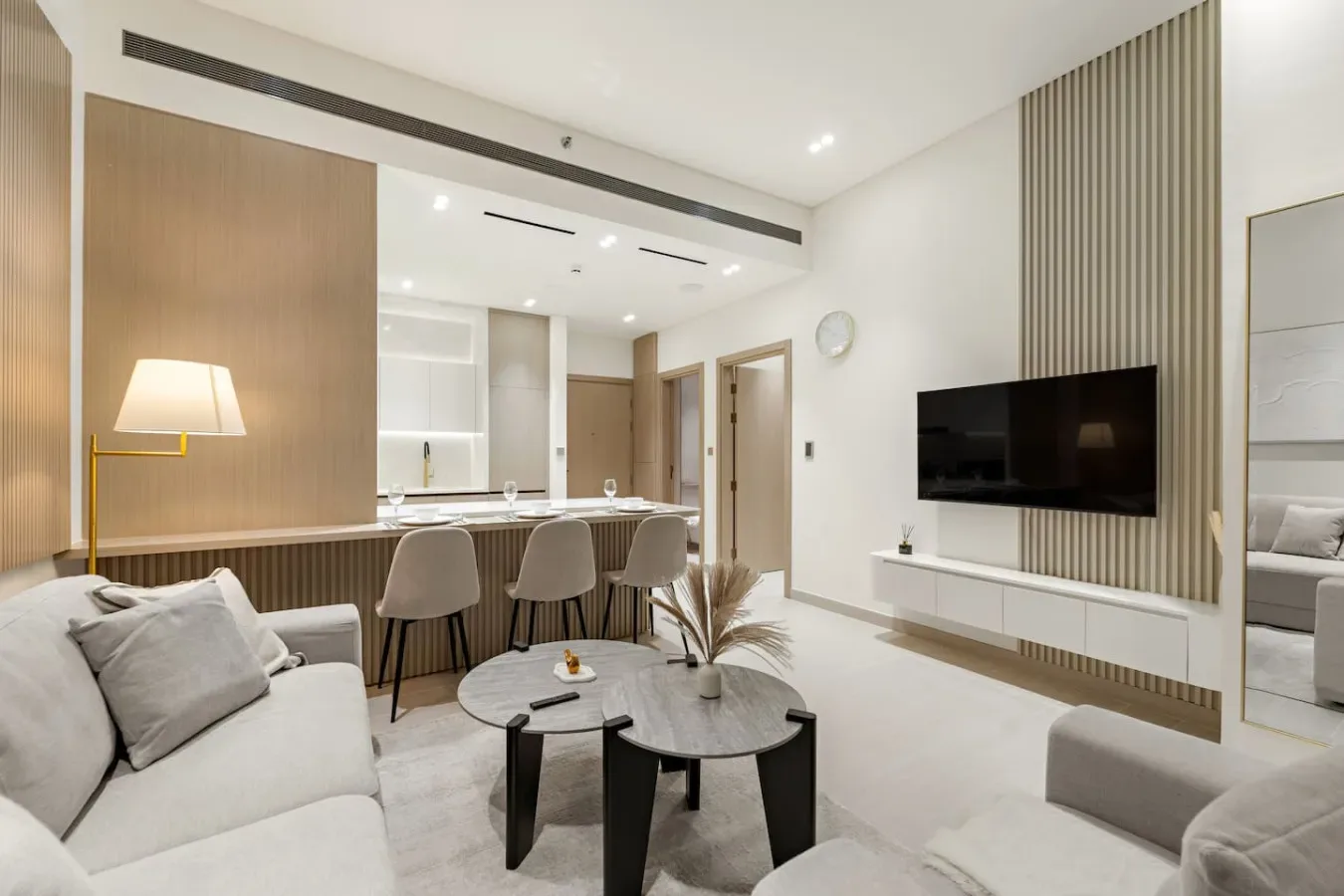Una sala luminosa con un sofá, mesas redondas y un televisor.