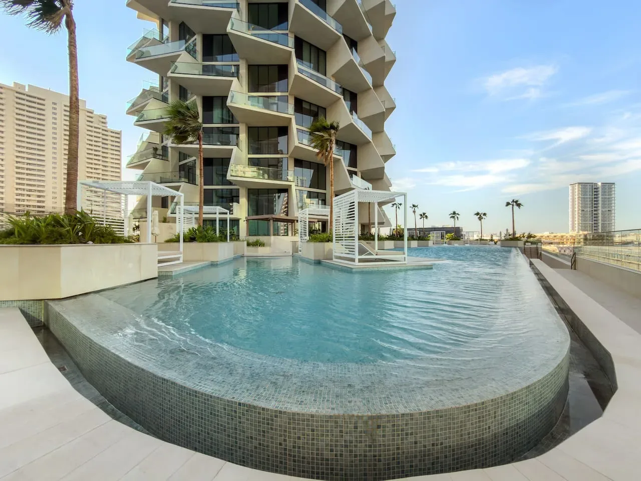 Una piscina en la azotea está junto a un moderno edificio alto.