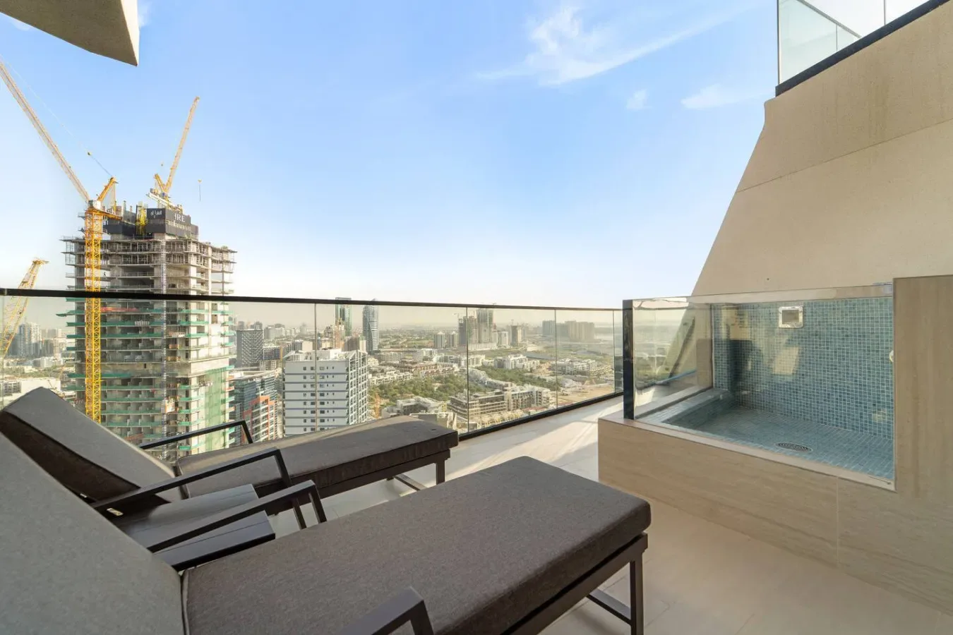 Una terraza en la azotea con asientos, una barandilla de vidrio y vistas de la ciudad.