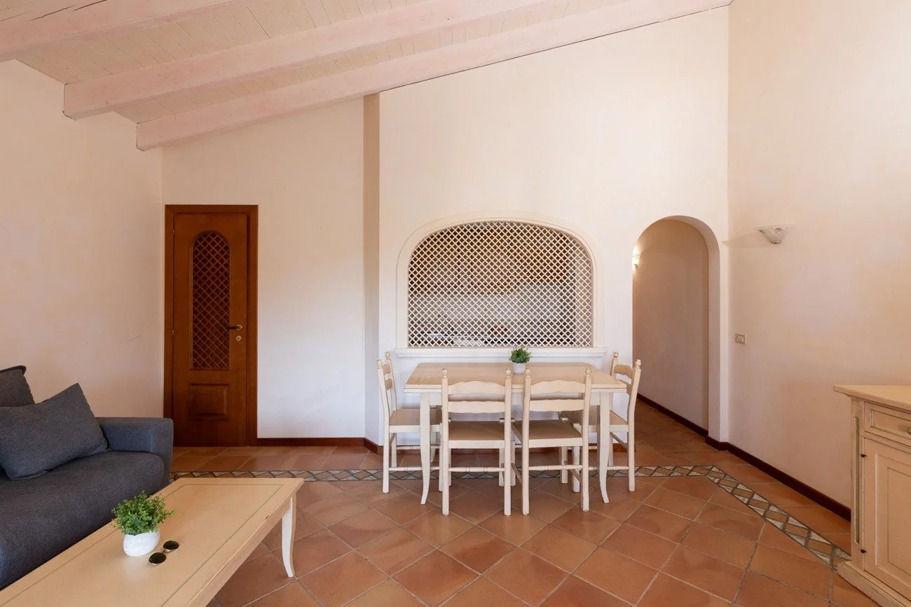 A dining area with a table and chairs beside a built-in arched wall niche.