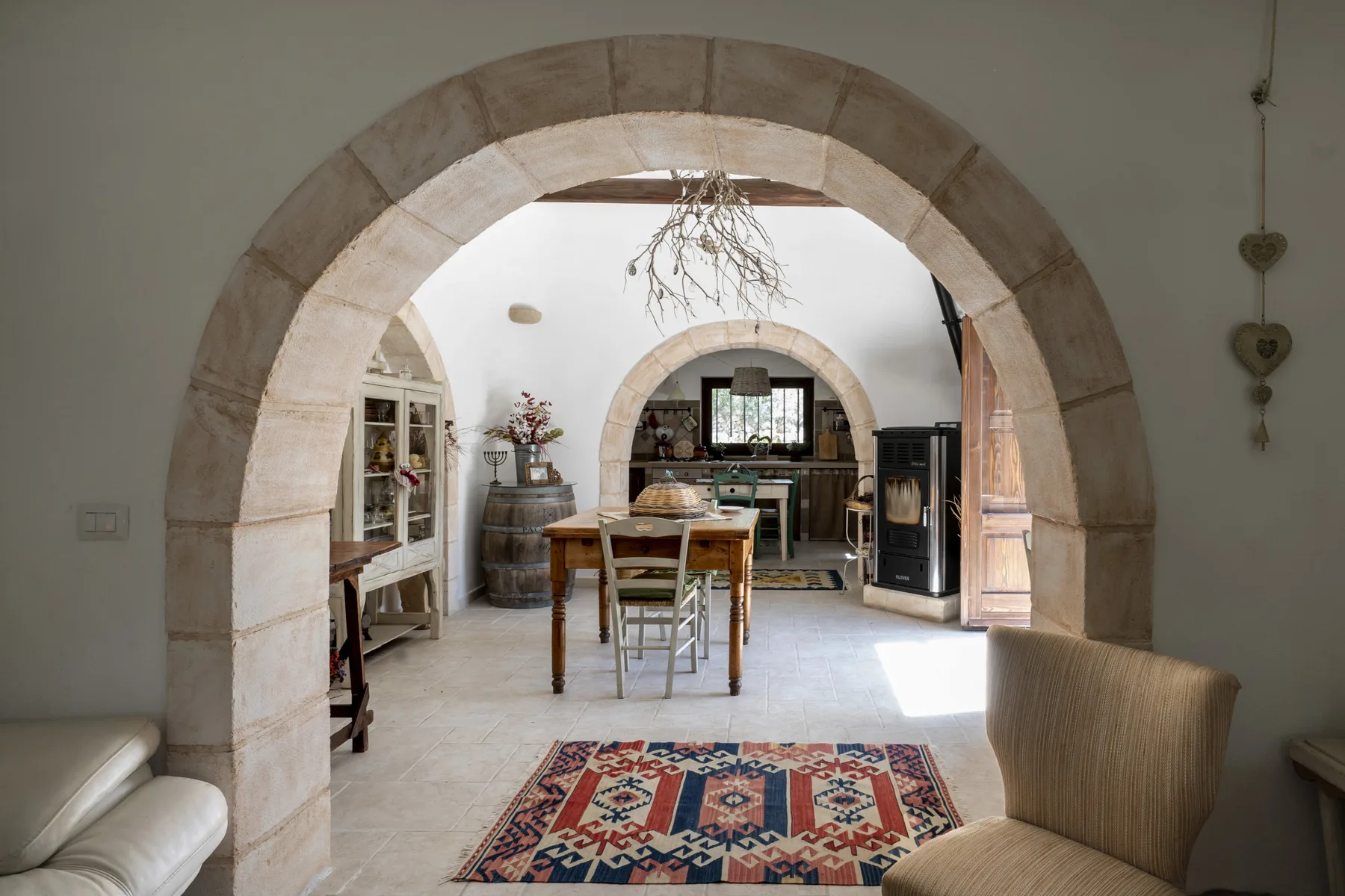 Comedor enmarcado por un arco de piedra, con una mesa y una alfombra estampada.