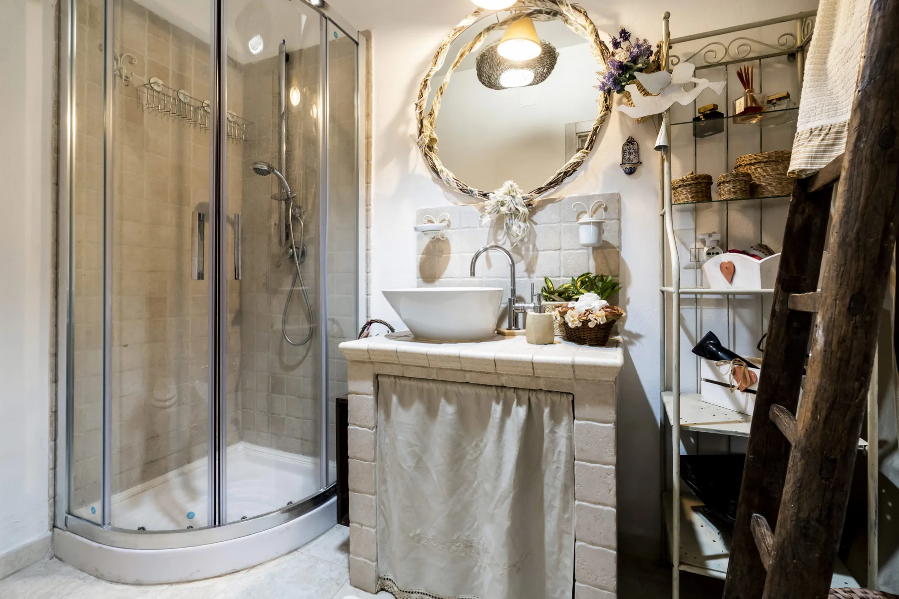 Un baño con una ducha de vidrio, un lavabo y un espejo redondo.