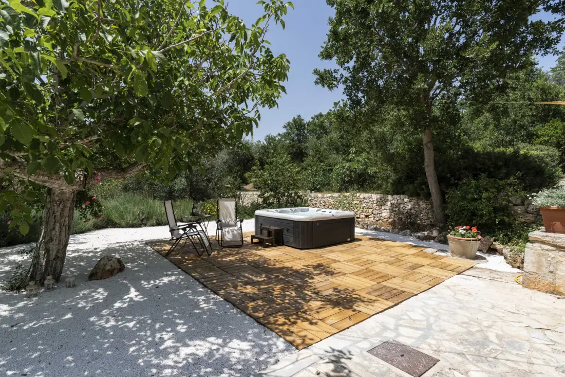 Un patio al aire libre con jacuzzi, asientos y árboles alrededor.